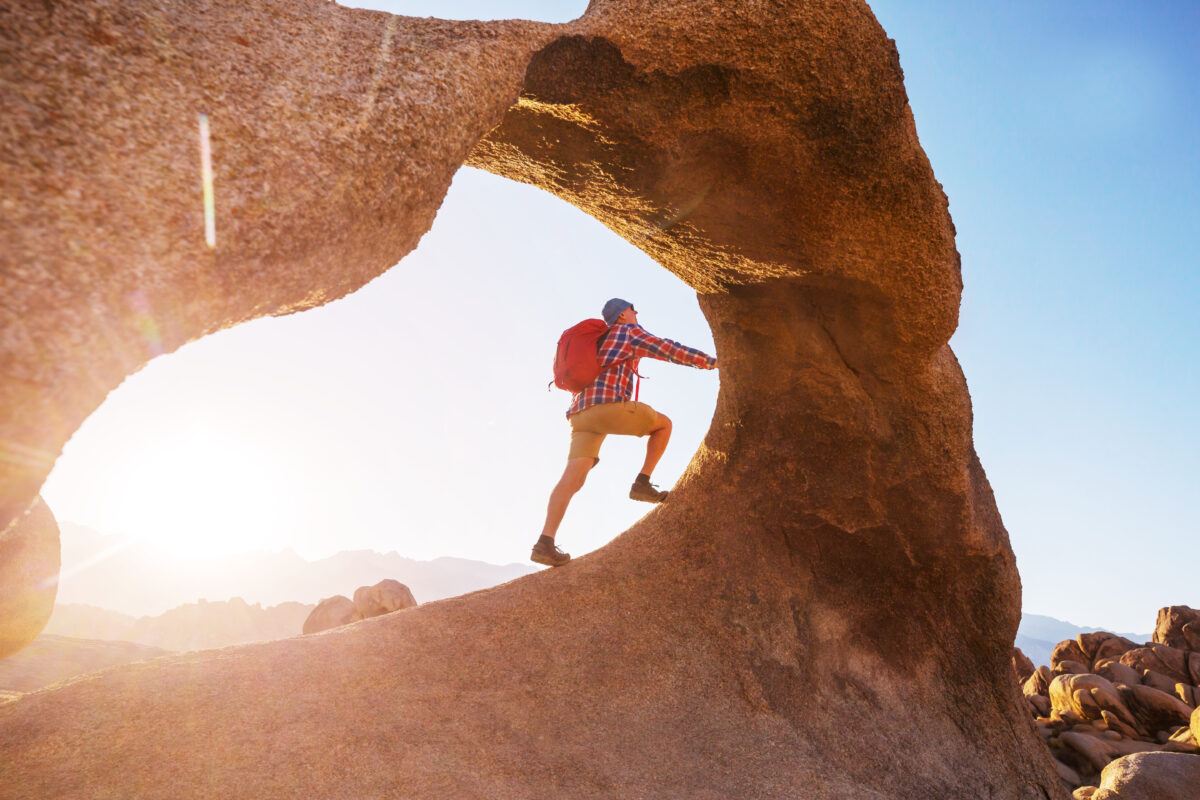 Man climbing an arch inthe Utah desert