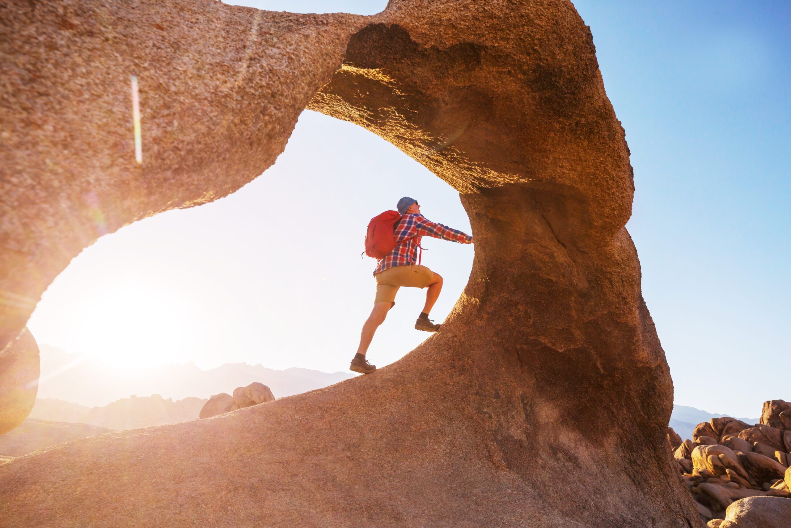 Man climbing an arch inthe Utah desert