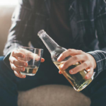 Man with alcoholism pouring another glass of liqour